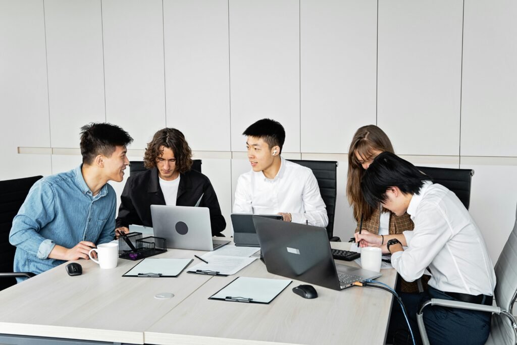A diverse group of coworkers engaged in a productive meeting with laptops in a contemporary office.
